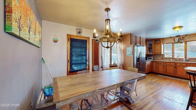 kitchen featuring brown cabinets, tasteful backsplash, hanging light fixtures, glass insert cabinets, and stainless steel fridge with ice dispenser