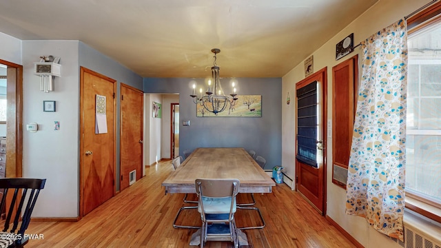 dining space featuring light wood-style floors, a baseboard radiator, visible vents, and a notable chandelier