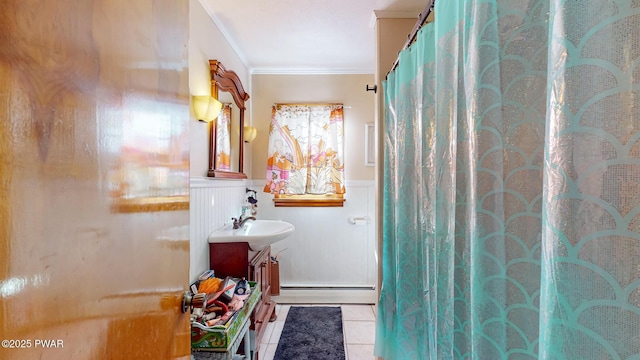 full bath with a baseboard radiator, tile patterned flooring, vanity, wainscoting, and crown molding