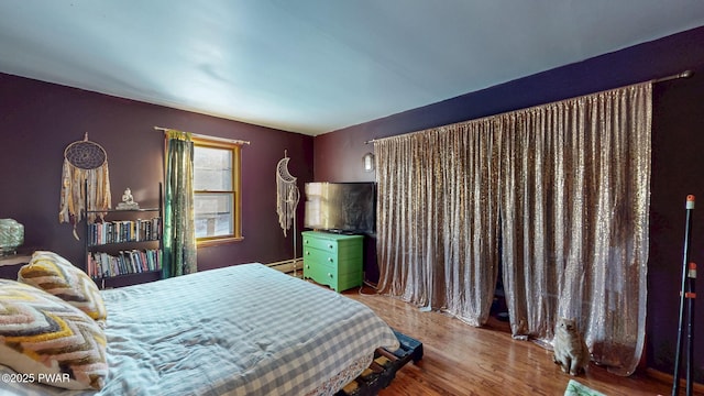 bedroom with baseboard heating and wood finished floors