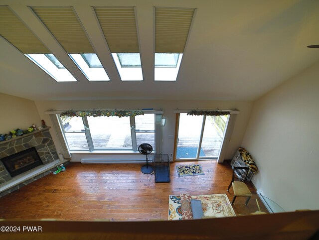 living room with baseboard heating, a fireplace, hardwood / wood-style floors, and plenty of natural light