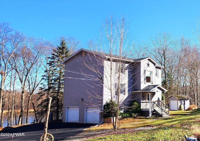 view of home's exterior featuring an outbuilding, an attached garage, a lawn, and driveway