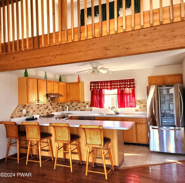 kitchen featuring decorative backsplash, a kitchen bar, kitchen peninsula, and stainless steel appliances