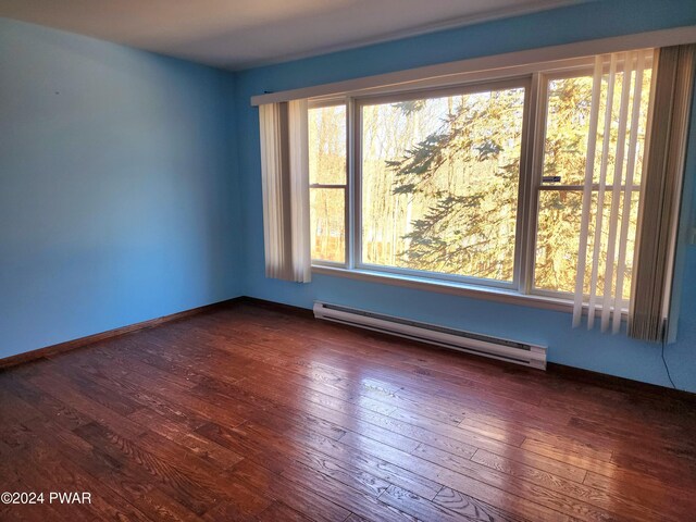 unfurnished room featuring baseboard heating and dark wood-type flooring