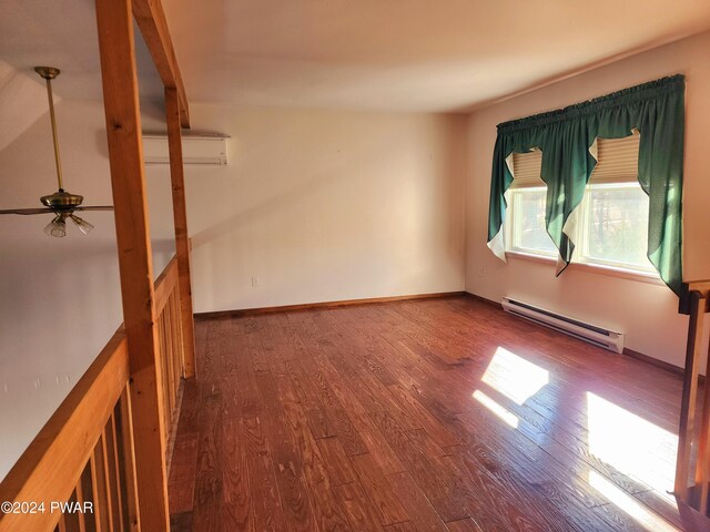 spare room with a wall mounted air conditioner, wood-type flooring, ceiling fan, and a baseboard heating unit