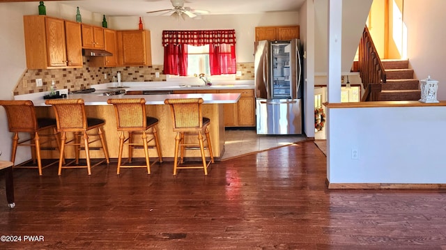 kitchen with dark wood-style floors, a peninsula, smart refrigerator, and under cabinet range hood