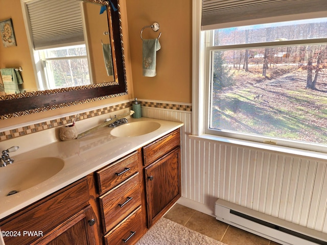 full bathroom with tile patterned flooring, baseboard heating, double vanity, and a sink