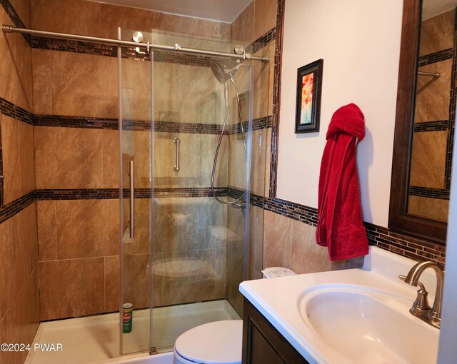 bathroom featuring a shower stall, vanity, tile walls, and toilet