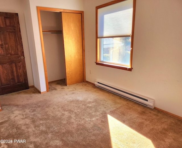 unfurnished bedroom with a closet, a baseboard heating unit, baseboards, and carpet floors