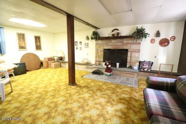 carpeted living room featuring a stone fireplace