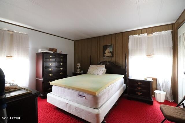 bedroom with dark carpet and wooden walls