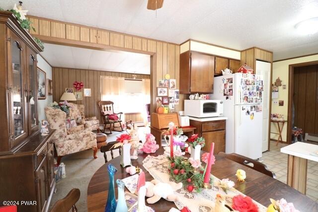 dining space featuring ceiling fan and wooden walls