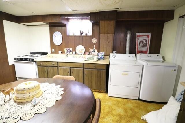 laundry area with wooden walls, washer and clothes dryer, and light carpet