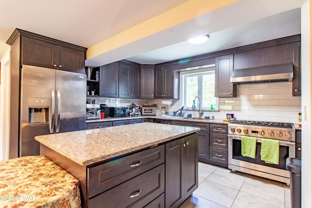 kitchen featuring light stone countertops, dark brown cabinetry, stainless steel appliances, extractor fan, and a center island