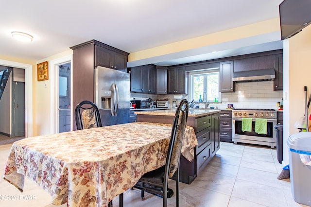 kitchen with decorative backsplash, dark brown cabinetry, stainless steel appliances, extractor fan, and a kitchen island