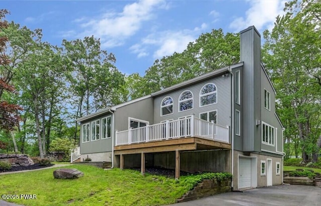 103 Goldrush Dr, Lords Valley, PA 18428 - back of house featuring a wooden deck, a garage, asphalt driveway, a lawn, and a chimney