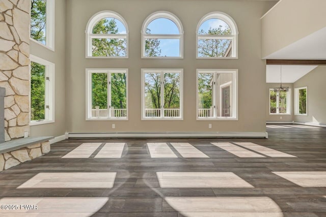 103 Goldrush Dr, Lords Valley, PA 18428 - unfurnished living room featuring a towering ceiling, a baseboard heating unit, and wood finished floors