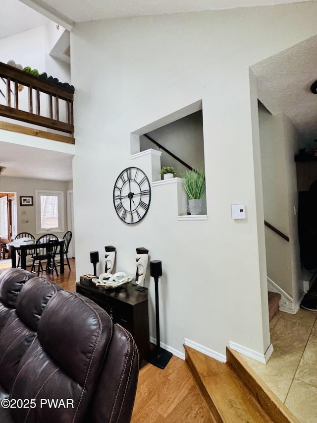 living area with high vaulted ceiling, stairway, baseboards, and wood finished floors