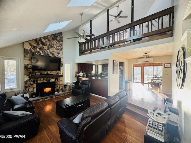 living room featuring a ceiling fan, dark wood-style flooring, a wall mounted air conditioner, and a stone fireplace