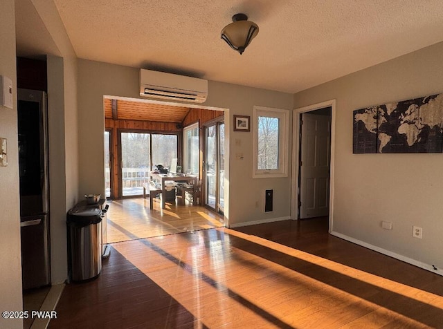 entrance foyer with dark wood-style flooring, a textured ceiling, baseboards, and a wall mounted AC