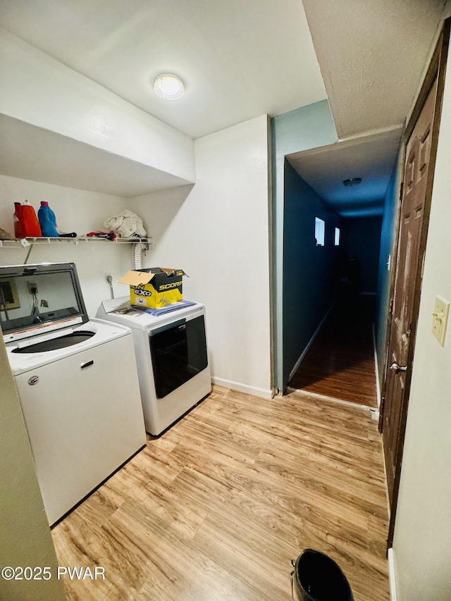 laundry area with light wood-type flooring, washer and dryer, laundry area, and baseboards