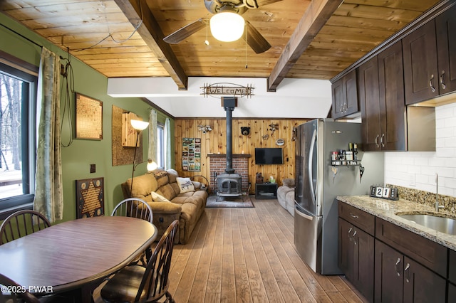 kitchen featuring open floor plan, dark brown cabinets, light stone counters, and freestanding refrigerator