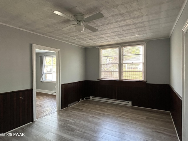 887 Maple Ave, Honesdale, PA 18431 - empty room featuring a ceiling fan, baseboard heating, wainscoting, and wood walls