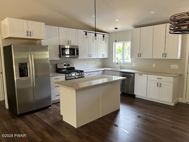 kitchen with appliances with stainless steel finishes, hanging light fixtures, white cabinetry, and a kitchen island