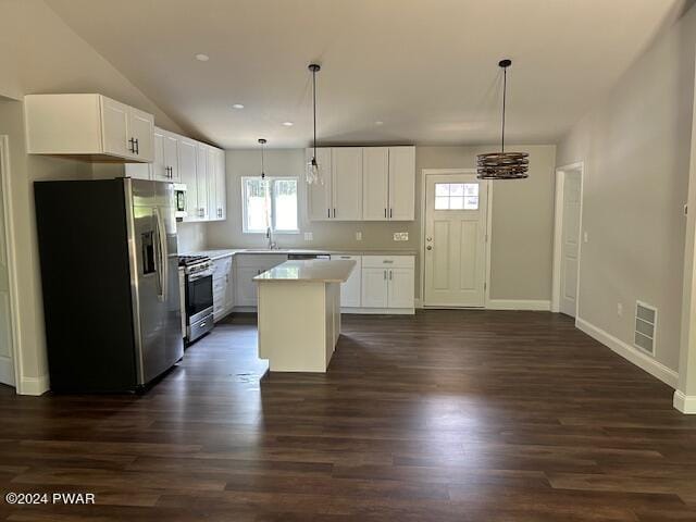 kitchen featuring appliances with stainless steel finishes, hanging light fixtures, dark wood-type flooring, a kitchen island, and white cabinetry