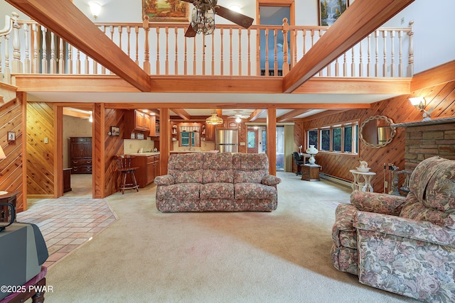 109 Glenbrook Dr, Dingmans Ferry, PA 18328 - carpeted living area featuring wood walls, a towering ceiling, ceiling fan, and baseboard heating