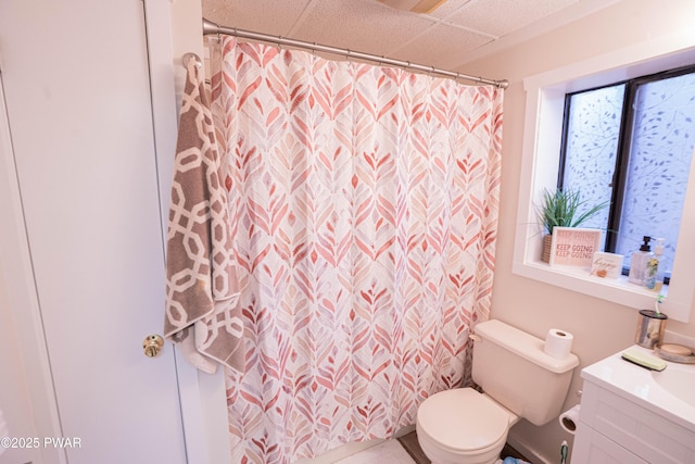 full bath featuring a shower with shower curtain, vanity, toilet, and a drop ceiling