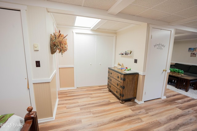 hall with light wood-style floors and a drop ceiling