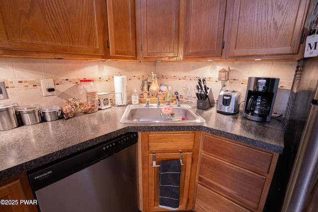 kitchen with dishwasher, dark countertops, backsplash, freestanding refrigerator, and a sink