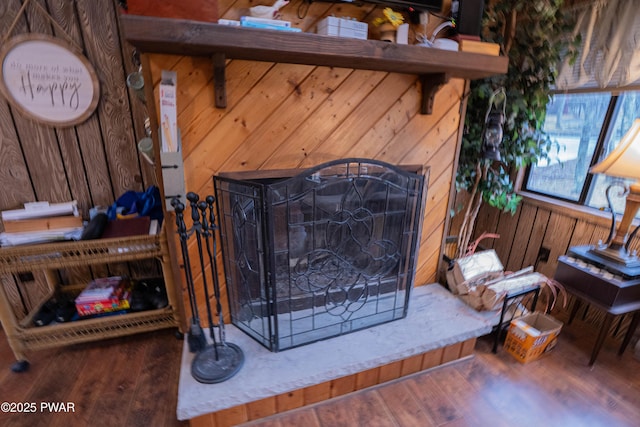 room details with wooden walls, a fireplace with raised hearth, and wood finished floors