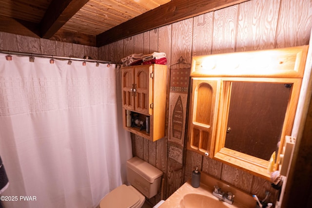 full bathroom with beam ceiling, curtained shower, toilet, wood ceiling, and a sink