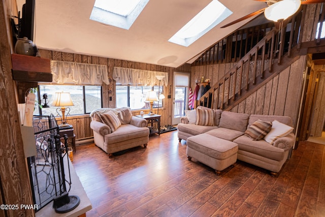 living area featuring lofted ceiling with skylight, dark wood-style flooring, and wood walls