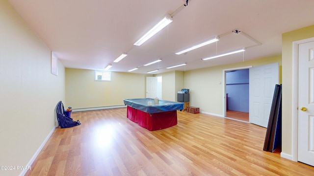 recreation room with light hardwood / wood-style flooring and a baseboard heating unit