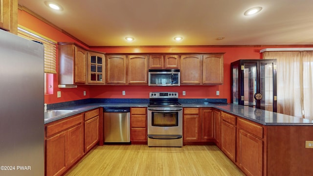 kitchen featuring stainless steel appliances, crown molding, light hardwood / wood-style floors, and sink