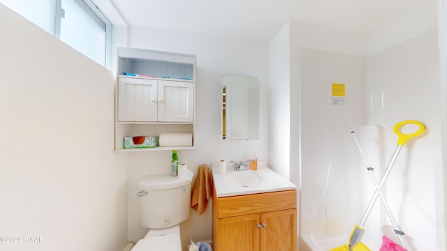 bathroom with walk in shower, vanity, and toilet