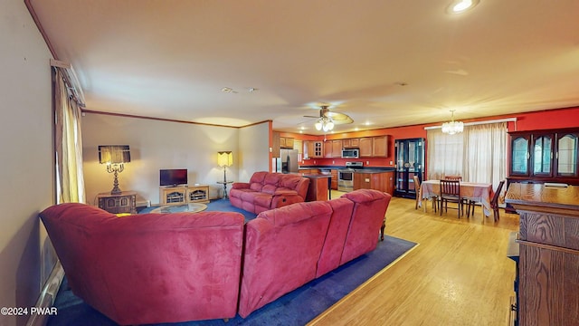 living room featuring ceiling fan with notable chandelier, light hardwood / wood-style floors, and ornamental molding