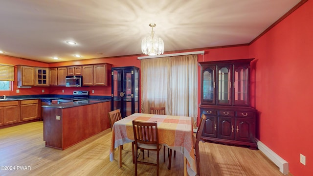 kitchen featuring stainless steel appliances, an inviting chandelier, light hardwood / wood-style flooring, decorative light fixtures, and ornamental molding