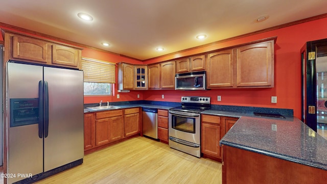 kitchen with ornamental molding, sink, light wood-type flooring, and appliances with stainless steel finishes