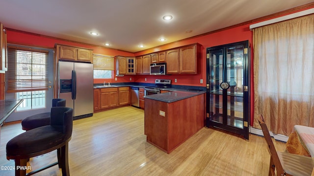 kitchen featuring light hardwood / wood-style floors, baseboard heating, stainless steel appliances, and a wealth of natural light