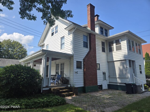 rear view of property featuring covered porch