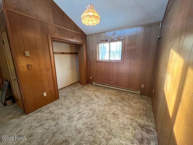 unfurnished bedroom with a baseboard radiator, lofted ceiling, wooden walls, and a textured ceiling