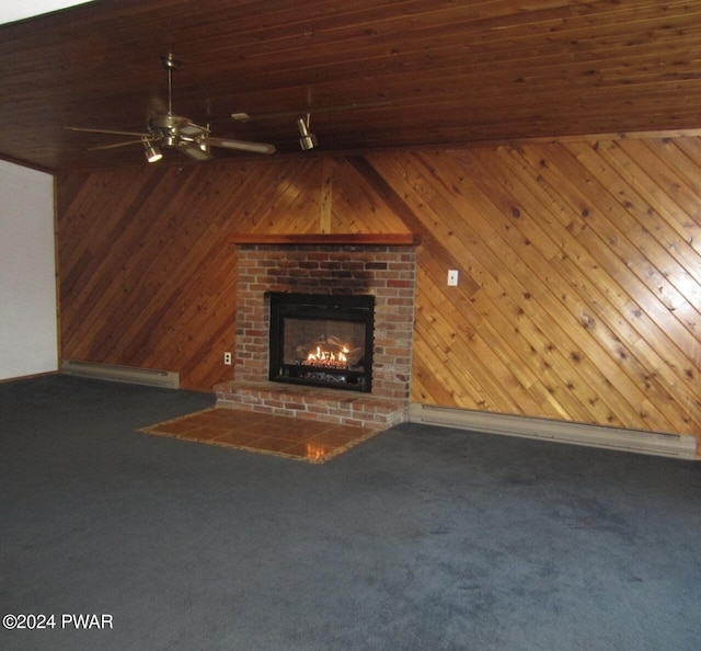 unfurnished living room featuring carpet flooring, ceiling fan, wood walls, and baseboard heating