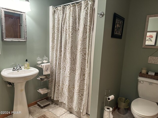 bathroom with tile patterned floors, curtained shower, toilet, and sink