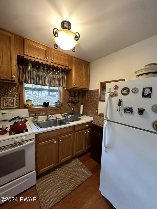 kitchen featuring white appliances, backsplash, dark hardwood / wood-style floors, and sink