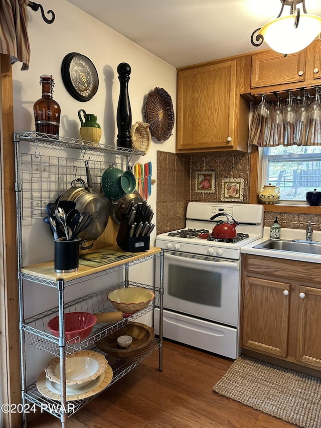 kitchen featuring tasteful backsplash, white range with gas cooktop, dark wood-type flooring, and sink