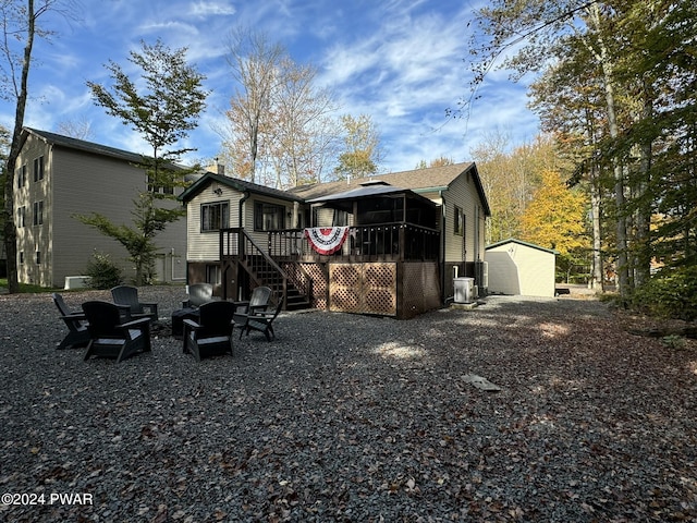 back of house featuring a sunroom and a storage unit